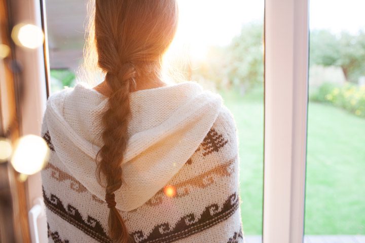 woman looking out window at beautiful sunshine