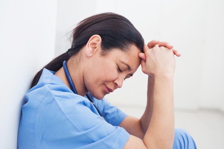 upset nurse or doctor leaning against wall - professionals