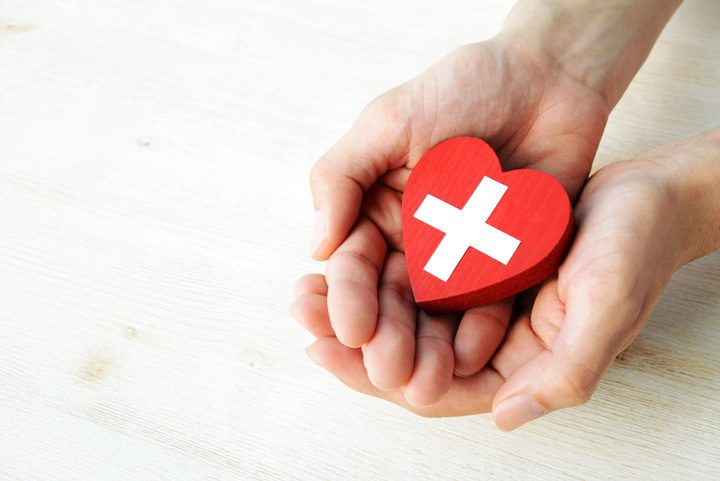 hands holding a red heart with white cross - safe detox