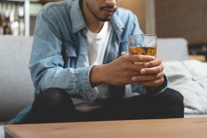 man in his early thirties sitting at home drinking liquor - alcohol consumption
